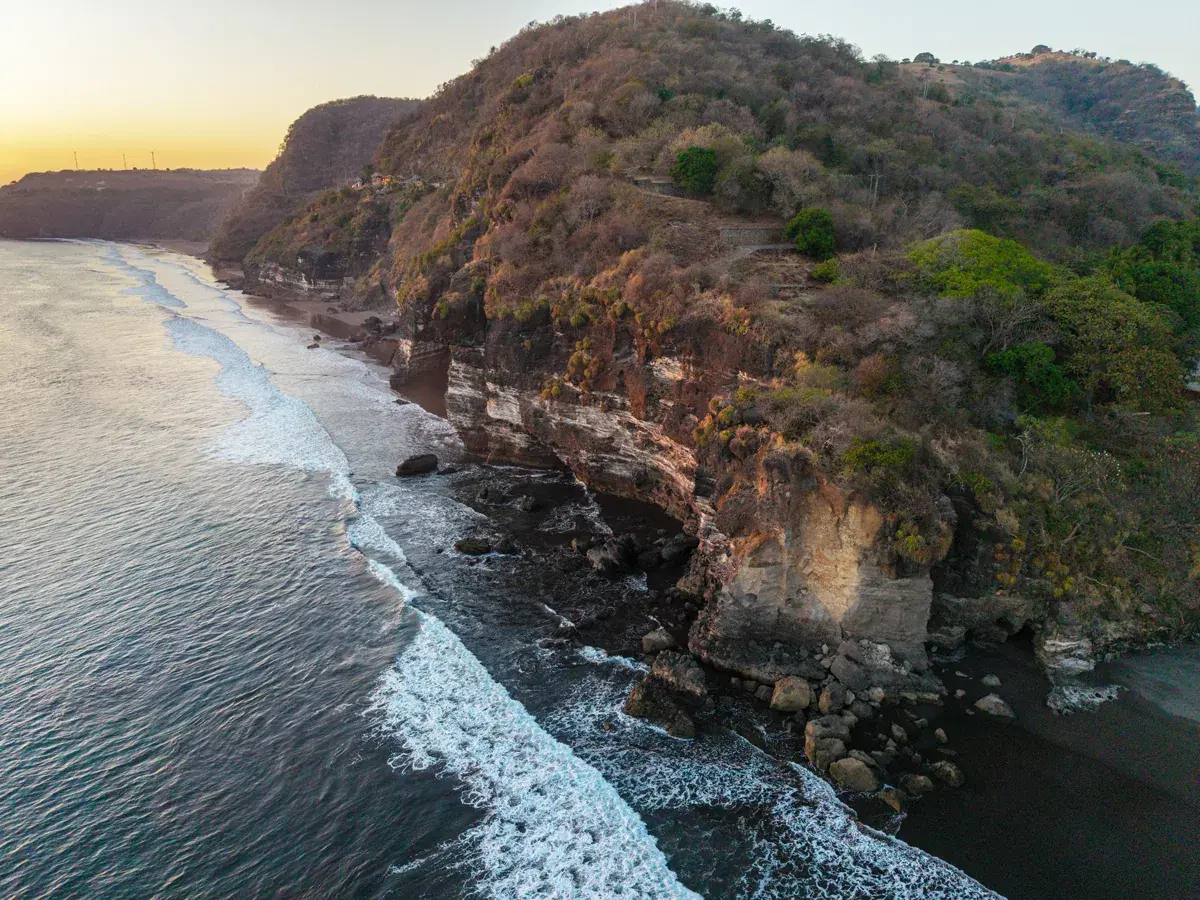 Mirador costero que enmarca la playa de arena y el borde rocoso del acantilado que define el terreno